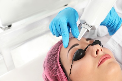 Woman undergoing laser tattoo removal procedure in salon, closeup