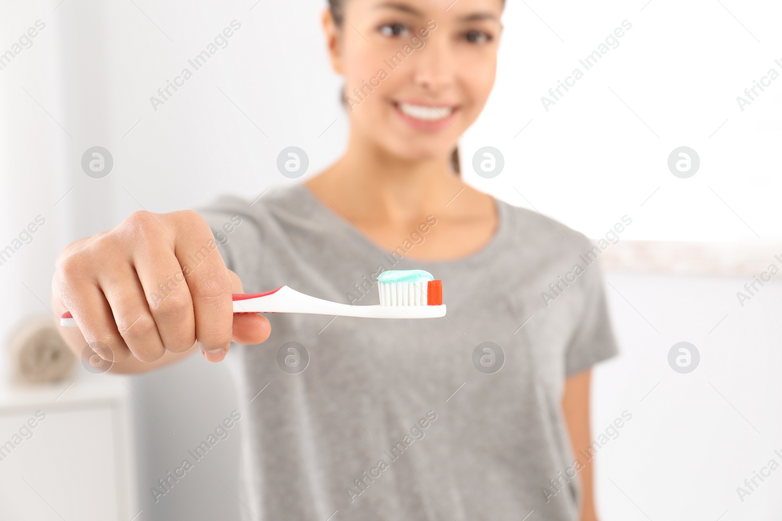 Photo of Young woman with toothbrush and paste in bathroom. Teeth care