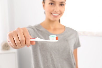 Photo of Young woman with toothbrush and paste in bathroom. Teeth care