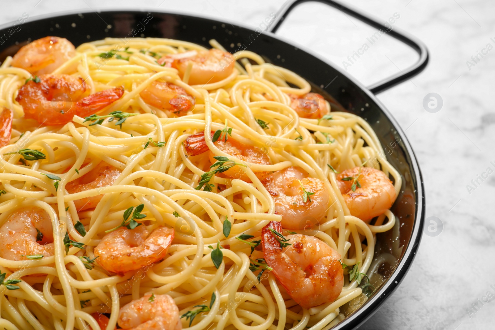 Photo of Frying pan with spaghetti and shrimps on light background