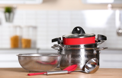 Photo of Set of clean cookware and utensils on table in kitchen