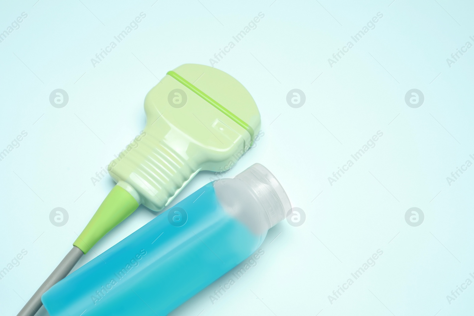 Photo of Ultrasonic transducer and ultrasound transmission gel on light background, closeup. Space for text