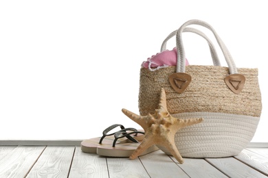 Stylish bag with beach accessories on white wooden table. Space for text