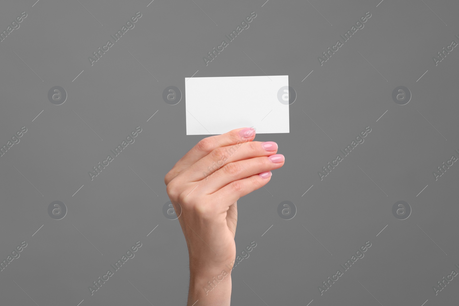 Photo of Woman holding blank business card on grey background, closeup. Space for text