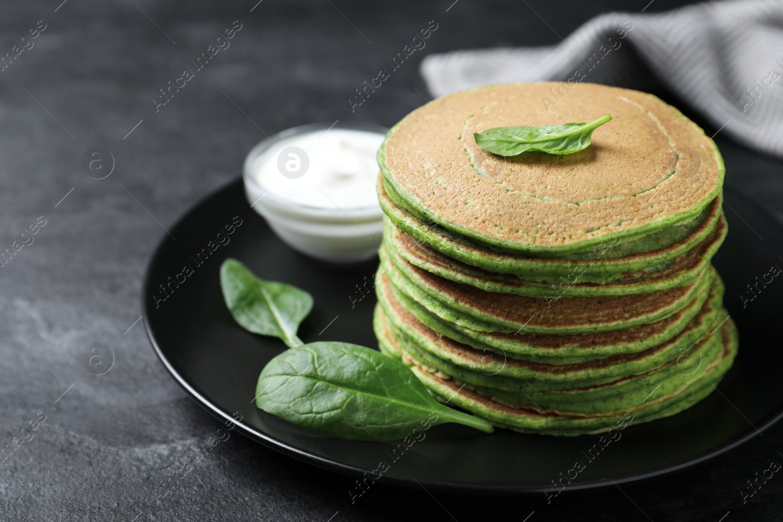 Photo of Tasty spinach pancakes on black table, closeup