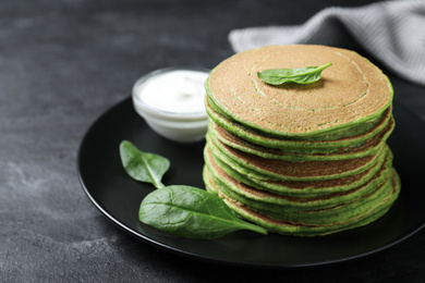 Photo of Tasty spinach pancakes on black table, closeup