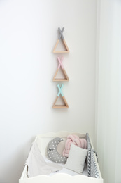 Photo of Wigwam shaped shelves over crib in baby room. Interior design