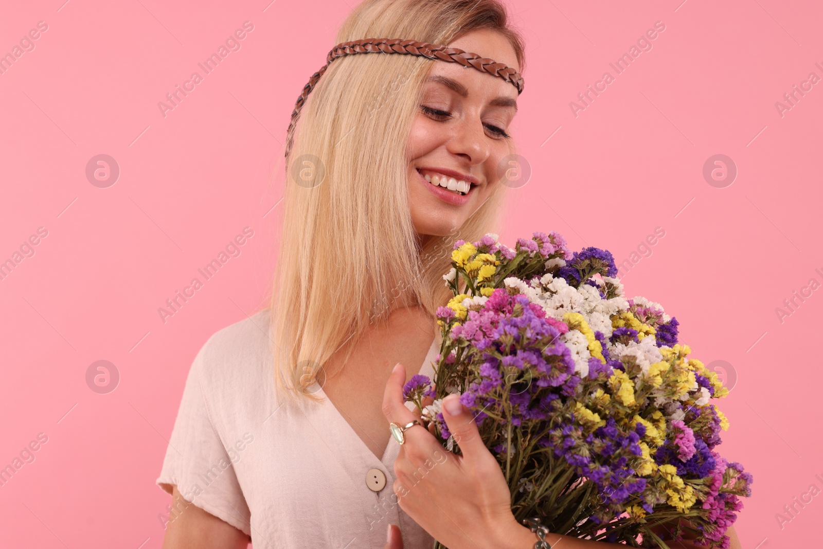 Photo of Portrait of smiling hippie woman with bouquet of flowers on pink background