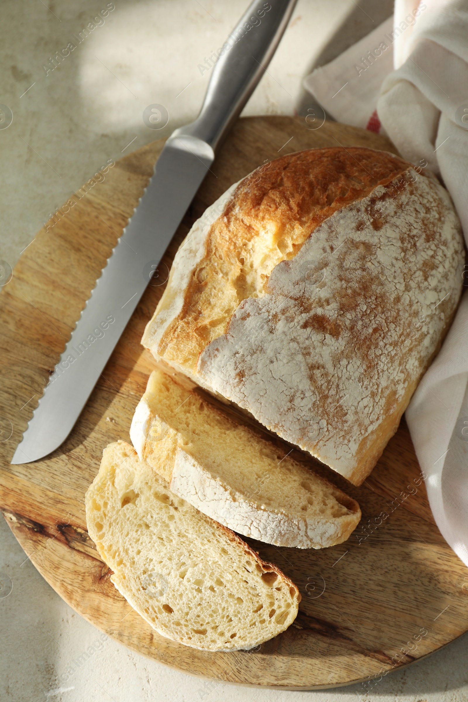 Photo of Freshly baked sourdough bread and knife on light table, top view