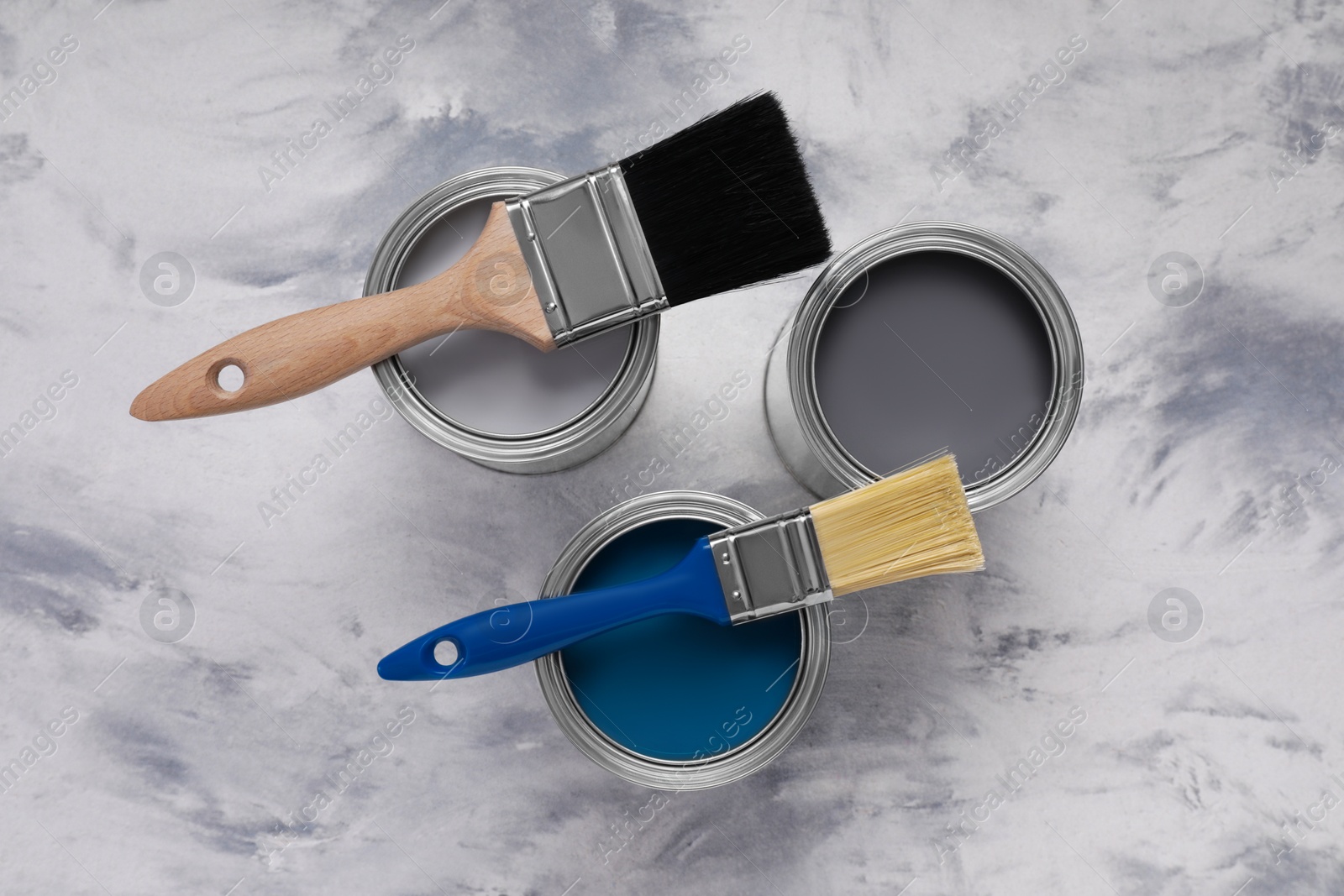 Photo of Cans of different paints and brushes on grey table, flat lay