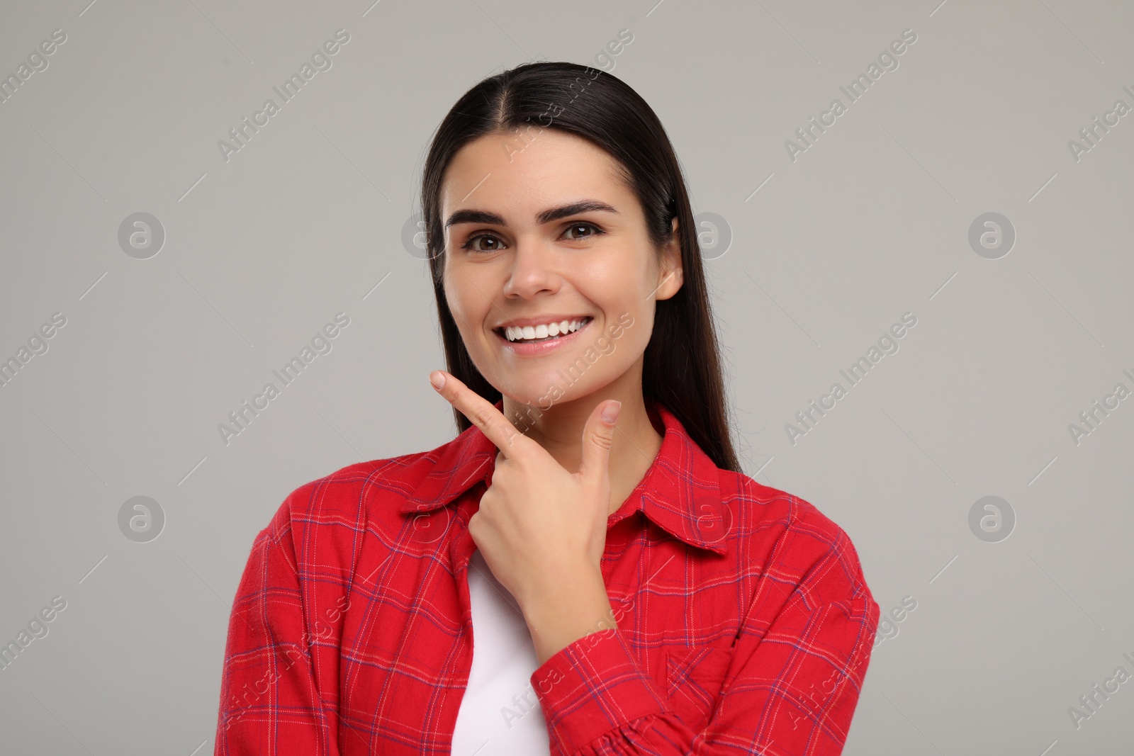 Photo of Young woman with clean teeth smiling on light grey background