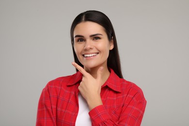 Photo of Young woman with clean teeth smiling on light grey background