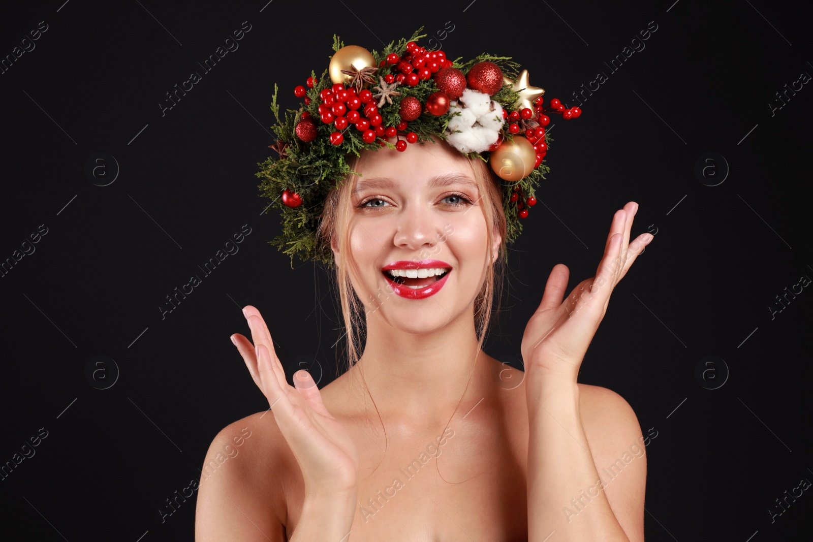 Photo of Beautiful young woman wearing Christmas wreath on black background