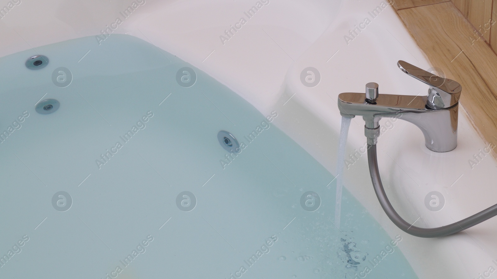 Photo of Water running into hot tub in bathroom