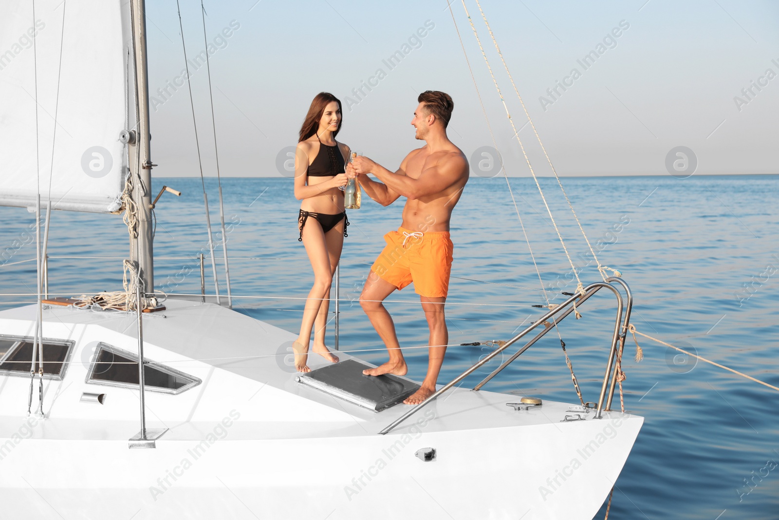 Photo of Young man and his girlfriend in bikini drinking champagne on yacht