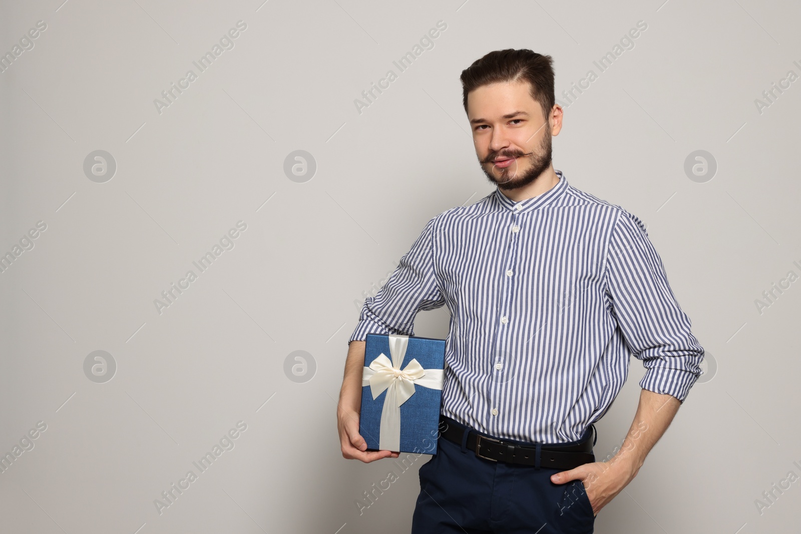 Photo of Happy man with gift on light grey background. Space for text