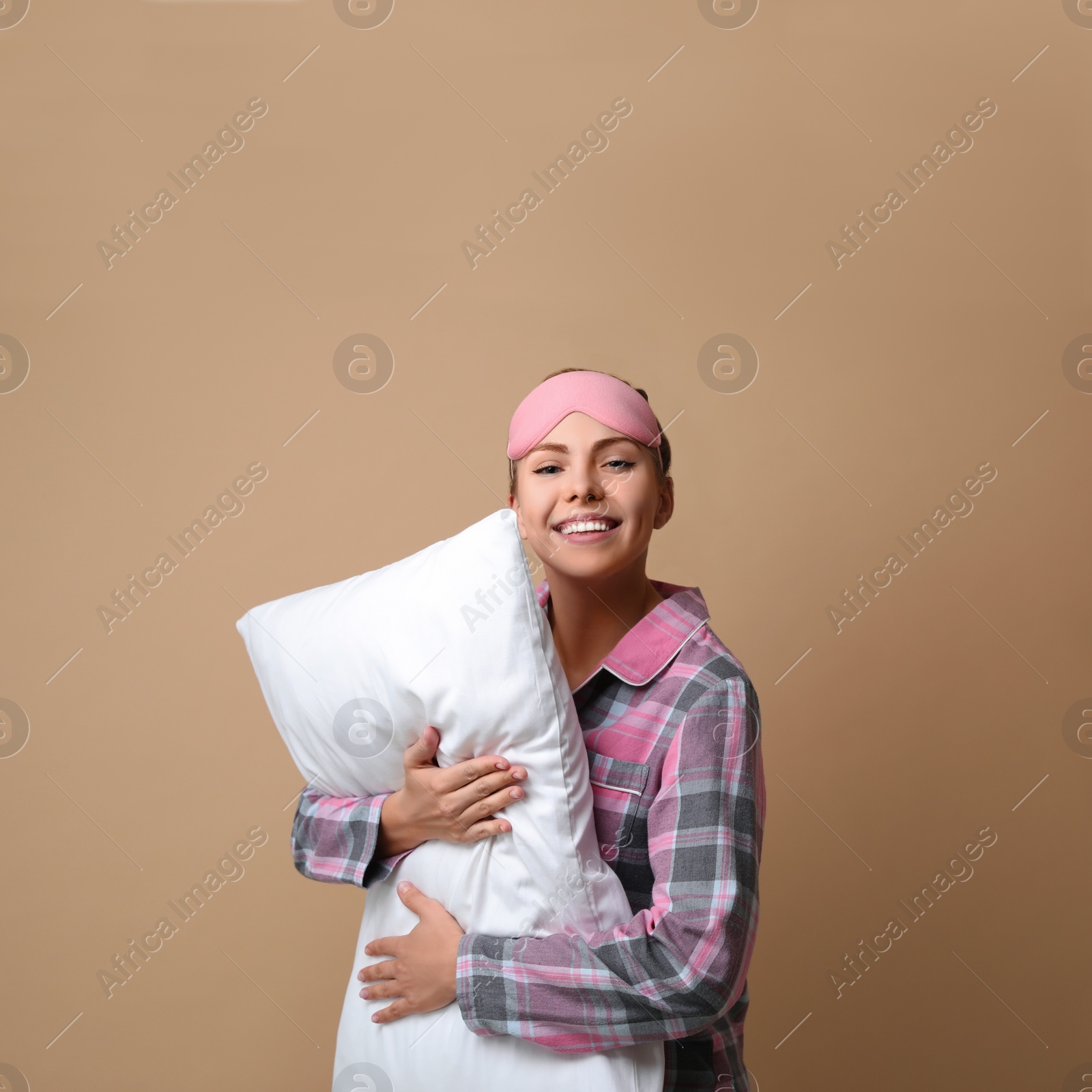 Photo of Beautiful woman with pillow on beige background. Bedtime