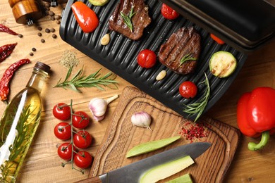 Flat lay composition with electric grill and different products on wooden table