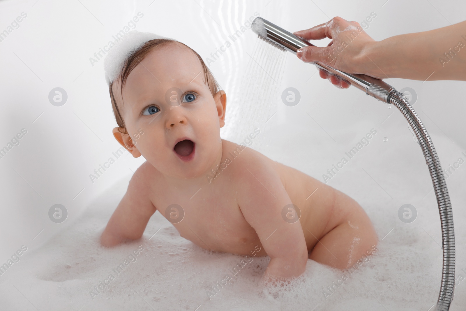 Photo of Mother washing her little baby in tub at home, closeup