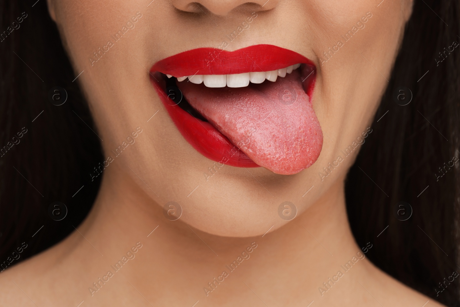 Photo of Woman with red lipstick showing her tongue, closeup