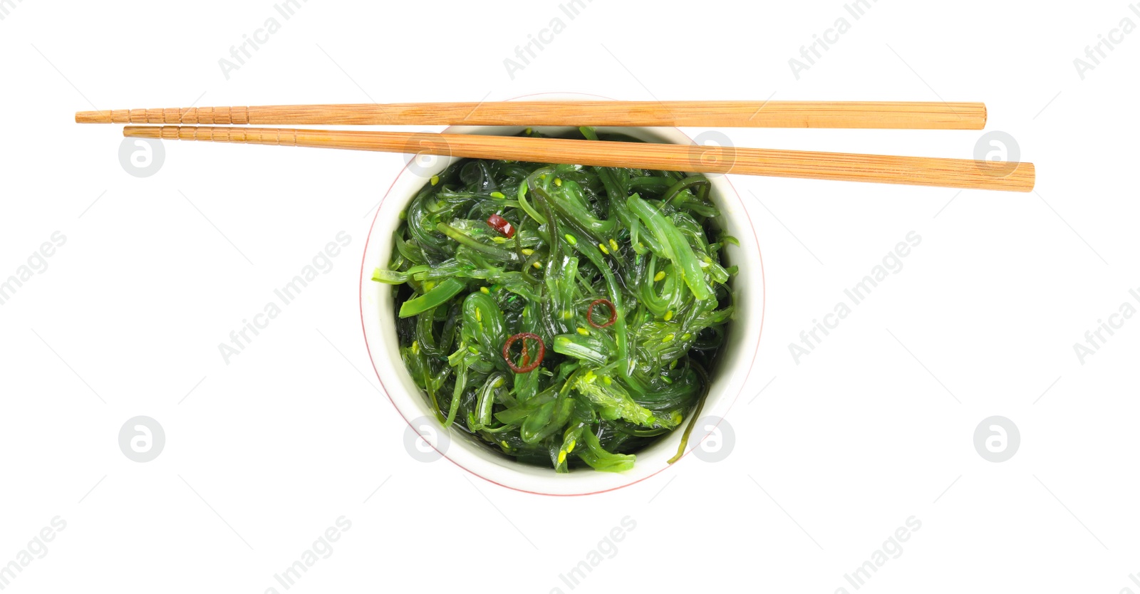 Photo of Japanese seaweed salad in bowl with chopsticks isolated on white, top view