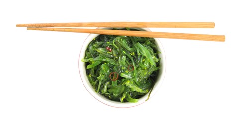 Photo of Japanese seaweed salad in bowl with chopsticks isolated on white, top view