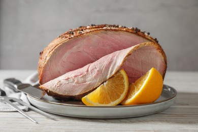Photo of Delicious baked ham and orange slices on white wooden table, closeup