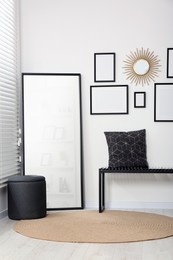 Photo of Stylish room interior with empty frames hanging on white wall and comfortable furniture