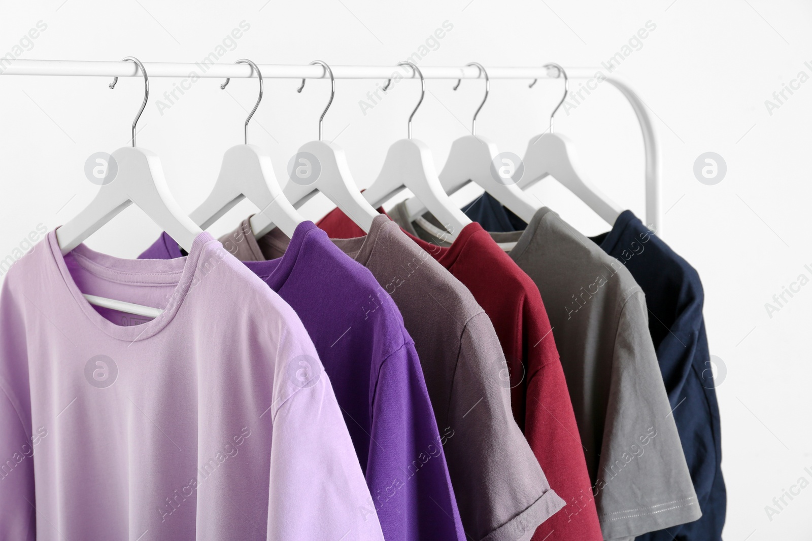 Photo of Men's clothes hanging on wardrobe rack against white background