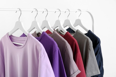 Photo of Men's clothes hanging on wardrobe rack against white background