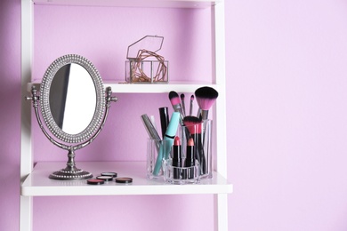 Photo of Organizer with makeup cosmetic products on shelf near color wall. Space for text