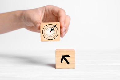 Image of Woman putting cube with icon of target on white background, closeup