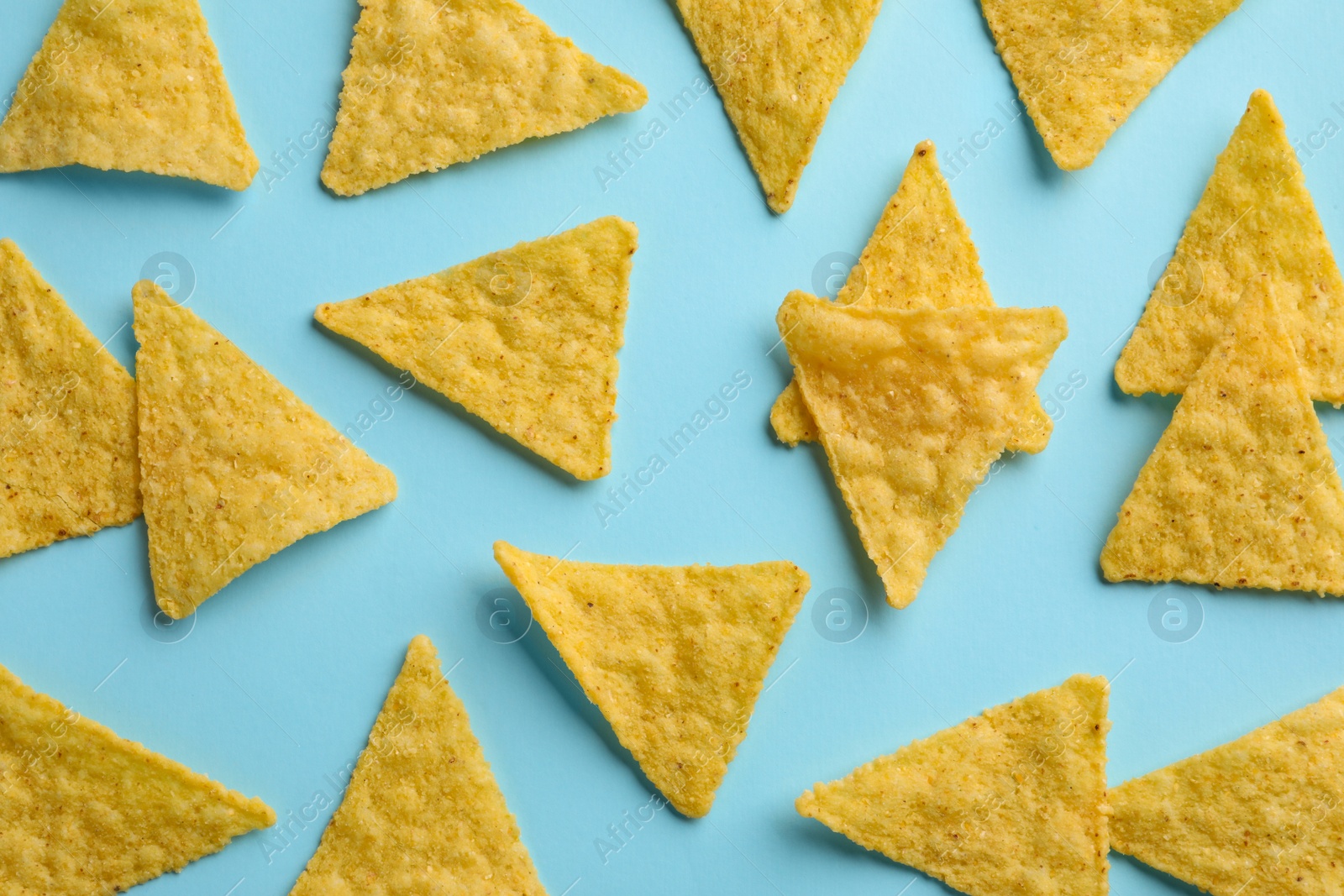 Photo of Flat lay composition of tasty tortilla chips (nachos) on light blue background