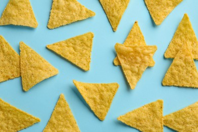 Flat lay composition of tasty tortilla chips (nachos) on light blue background