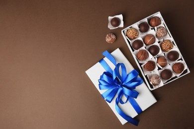 Photo of Box with delicious chocolate candies on brown background, flat lay. Space for text