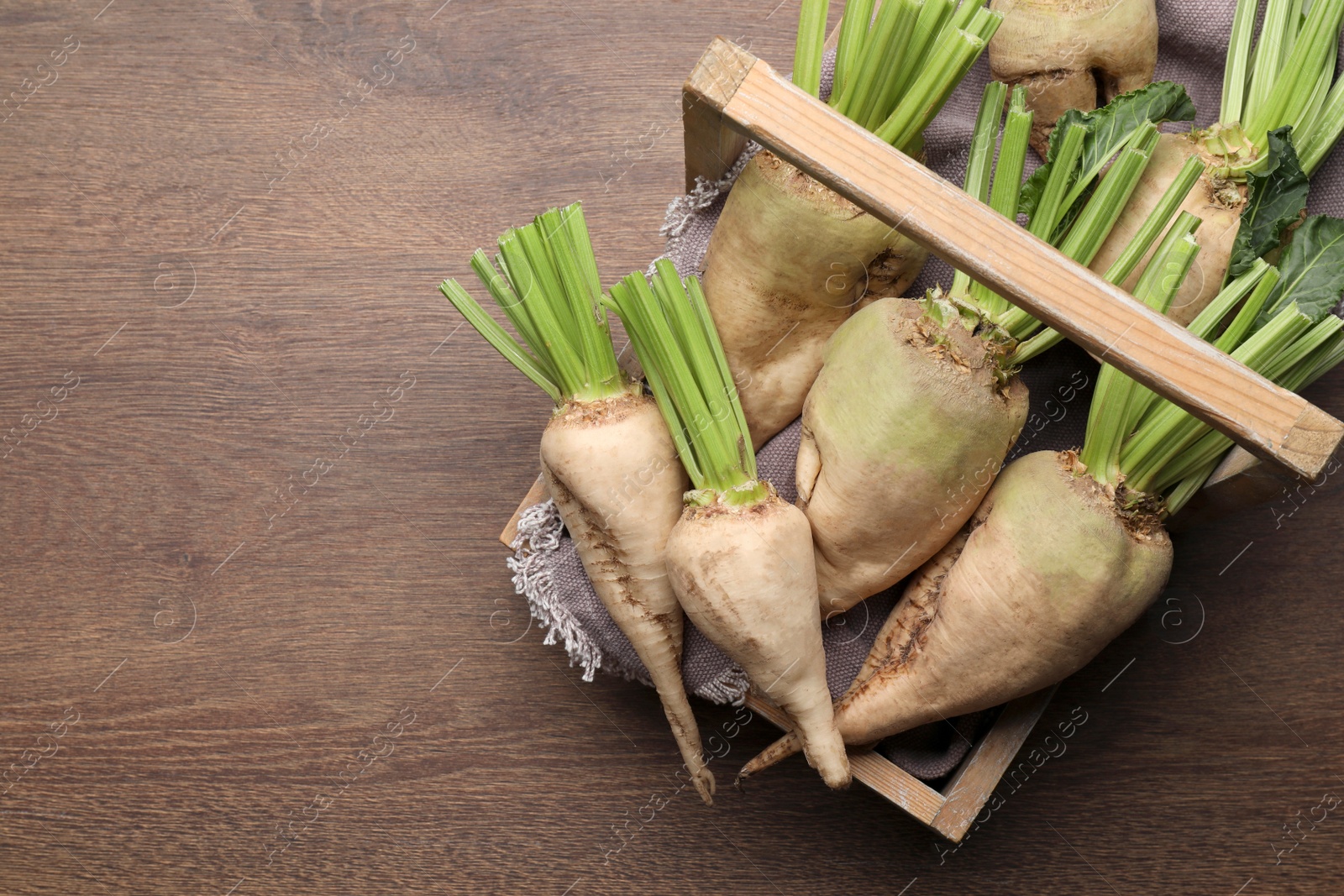 Photo of Basket with fresh sugar beets on wooden table, top view. Space for text