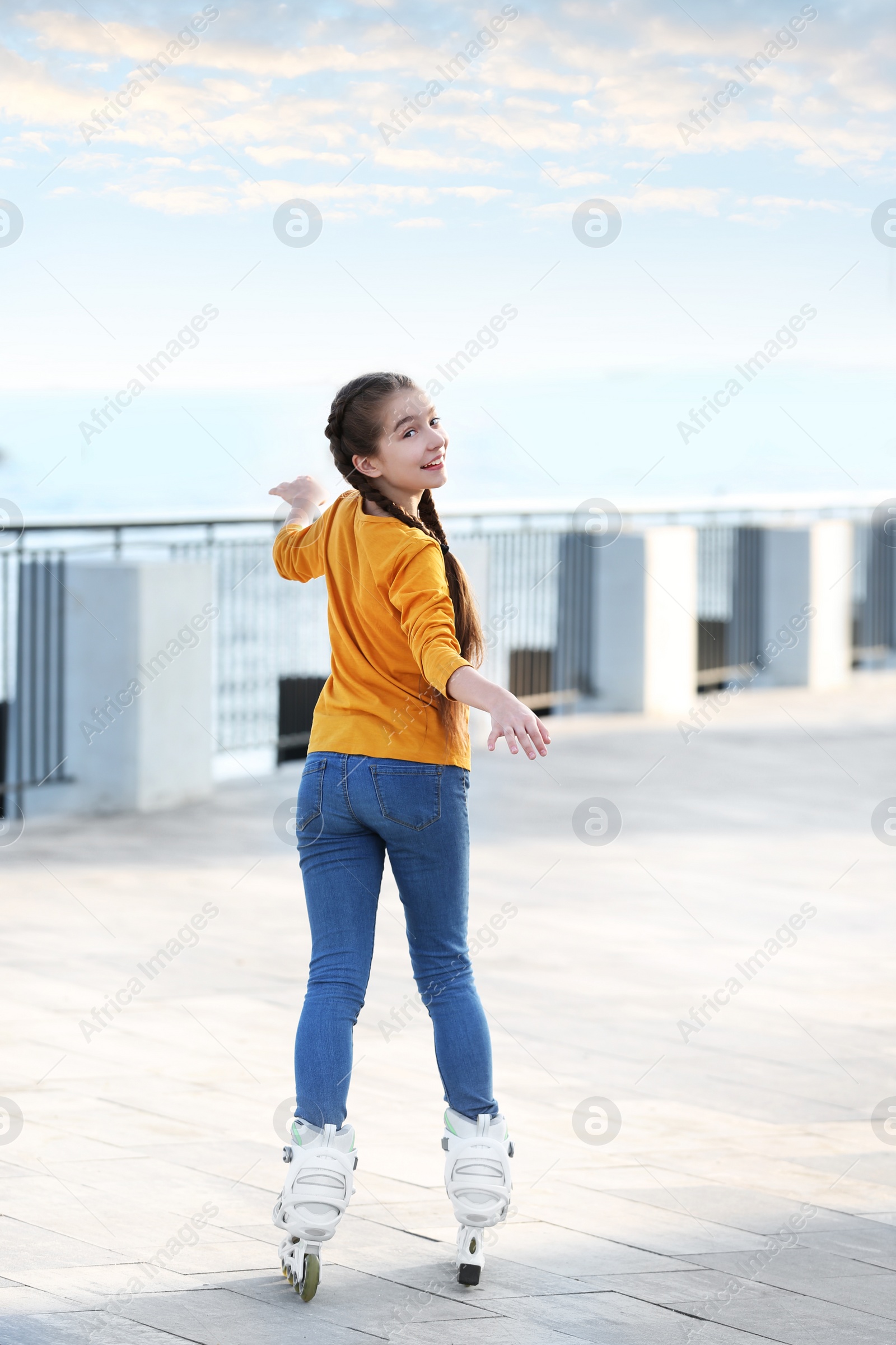 Photo of Little girl roller skating on city street