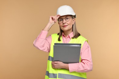 Photo of Architect in hard hat with folder on beige background