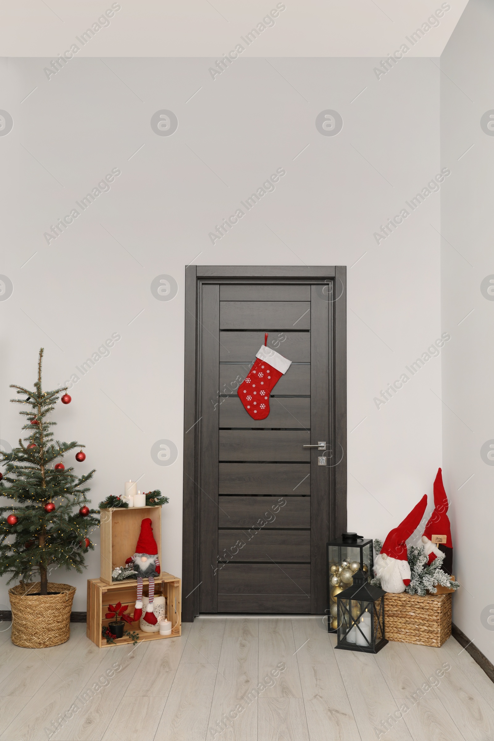 Photo of Christmas stocking hanging on wooden door and festive decoration indoors