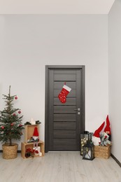 Photo of Christmas stocking hanging on wooden door and festive decoration indoors