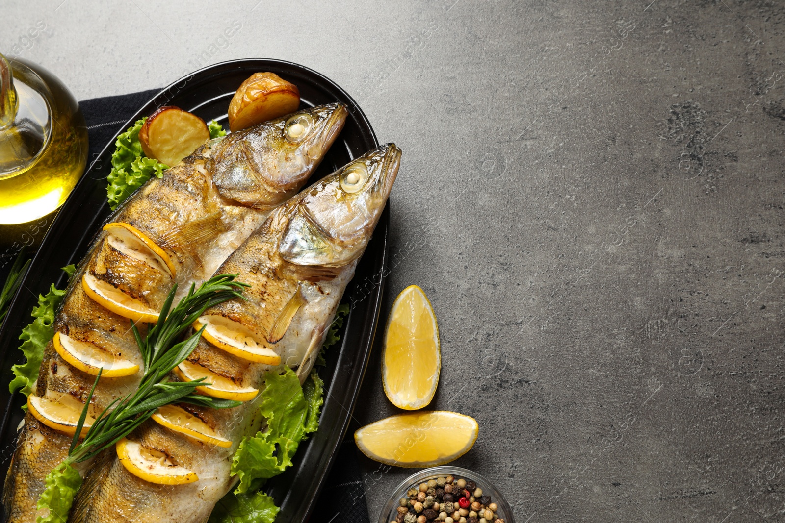 Photo of Tasty homemade roasted pike perches served on grey table, flat lay and space for text. River fish