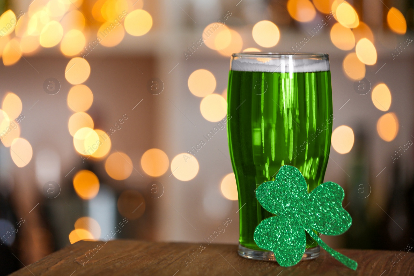 Photo of Green beer and clover on wooden counter, space for text. St.Patrick's Day celebration