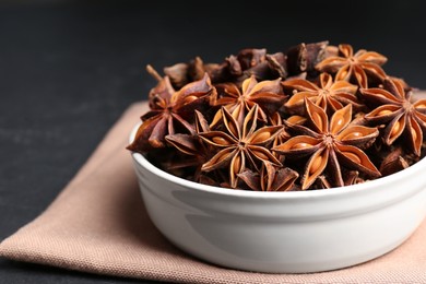 Photo of Bowl with aromatic anise stars on table, closeup