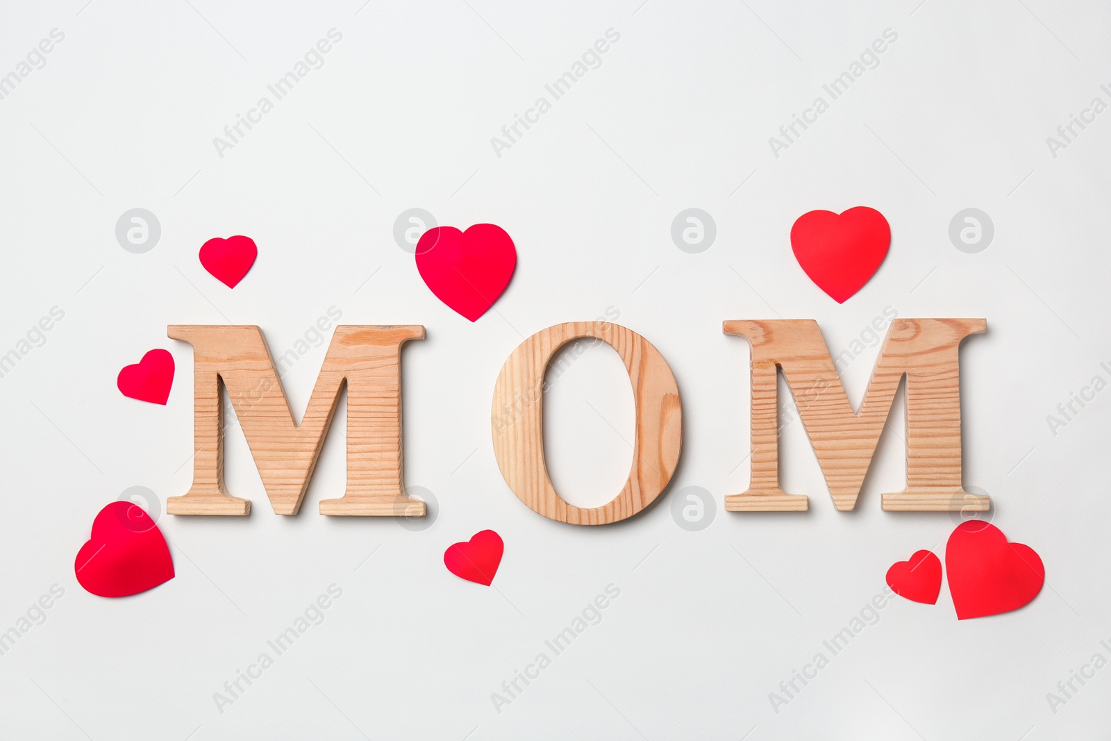 Photo of Word "MOM" made of wooden letters and paper hearts on white background. Happy Mother's Day