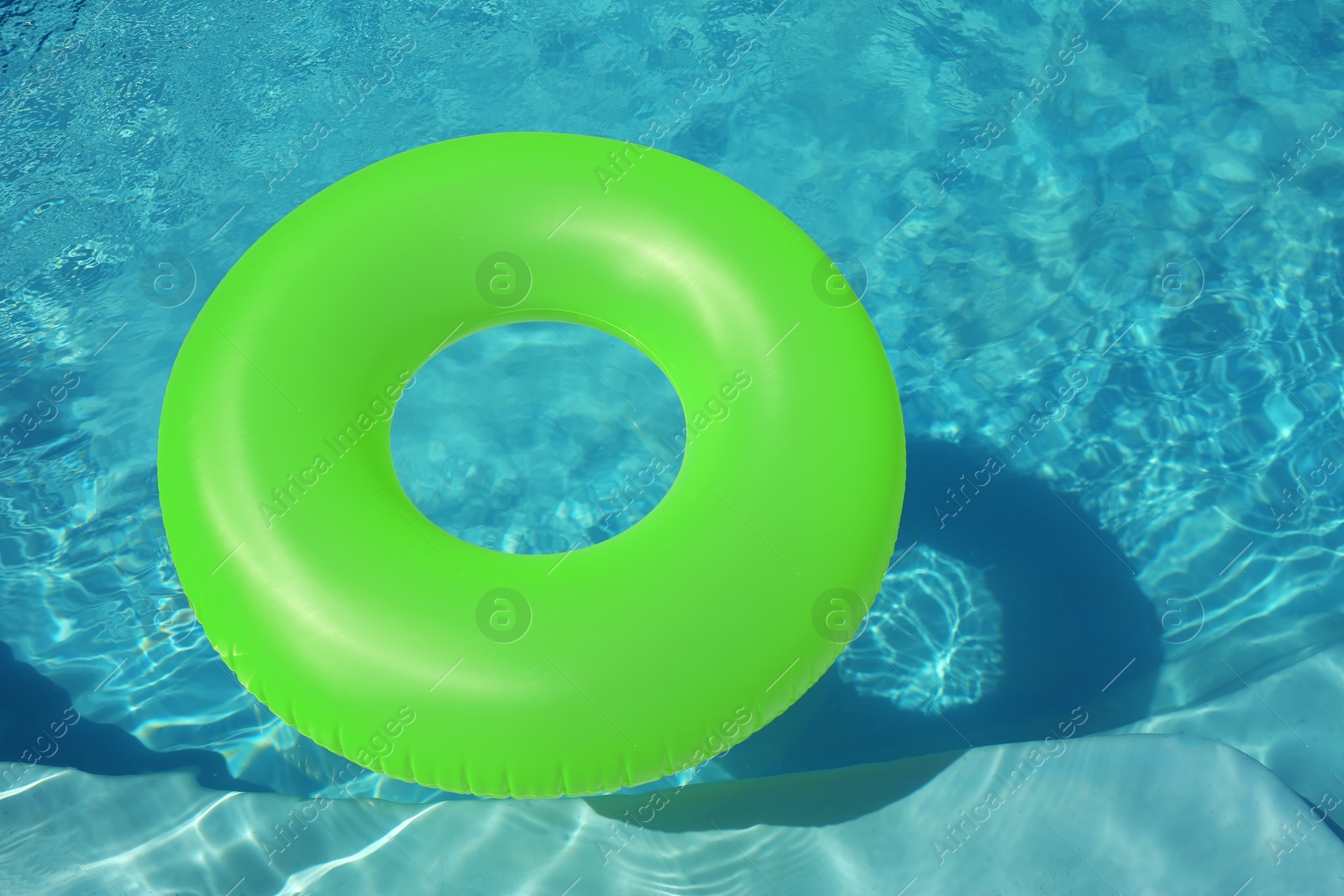 Photo of Bright inflatable ring floating in swimming pool on sunny day. Space for text