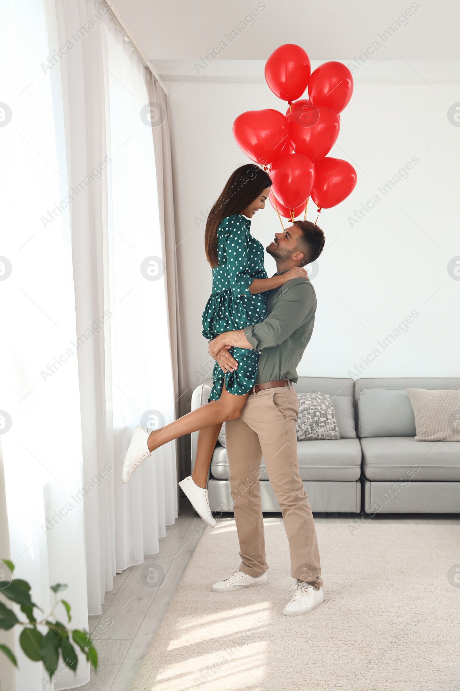 Photo of Young couple with air balloons at home. Celebration of Saint Valentine's Day