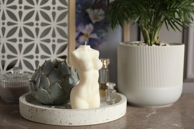 Beautiful female body shape candle, houseplant and decor on grey table