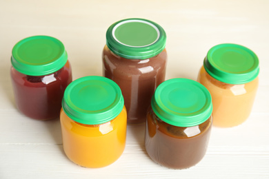 Photo of Jars with baby food on white wooden table