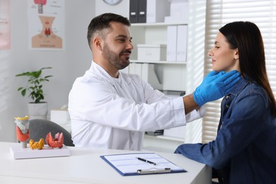 Endocrinologist examining thyroid gland of patient at table in hospital