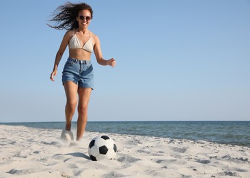Photo of African American woman playing football on beach. Space for text